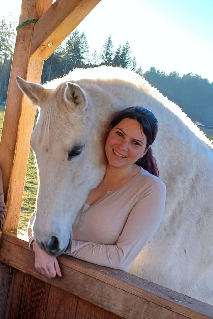 Lisa dunkelhaarige Frau mit hellem Shirt und Schimmel, der sich an sie lehnt.